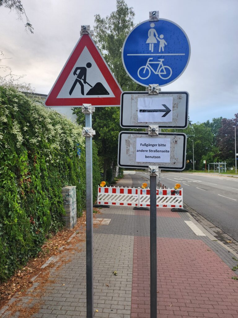 Baustellenschild und Fußgängerumleitung auf einem gesperrten Bürgersteig
