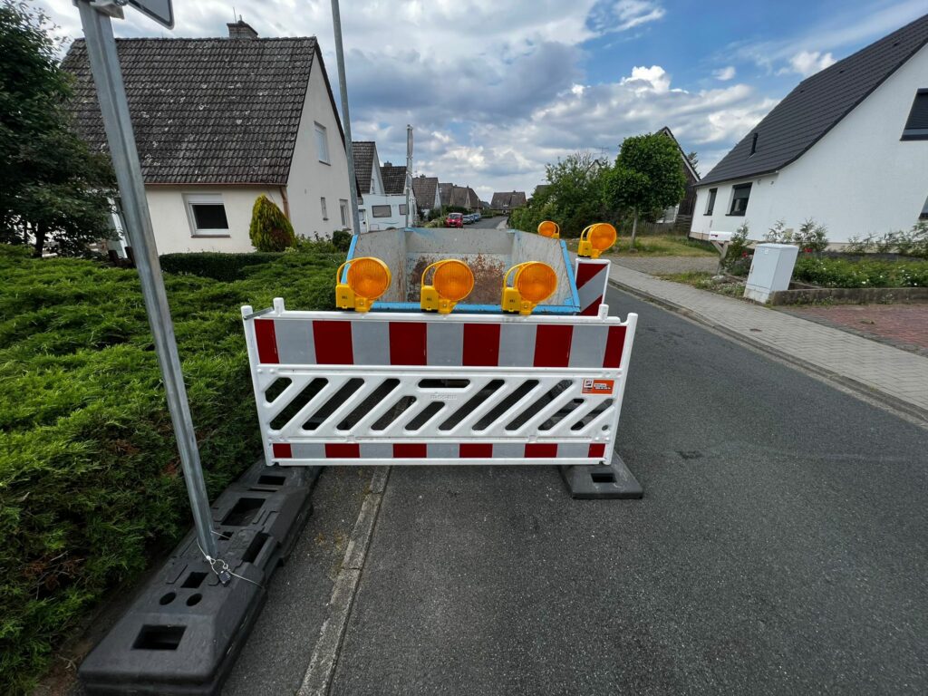 Absicherung mit Schranken und Warnlicht eines Containers am Straßenrand